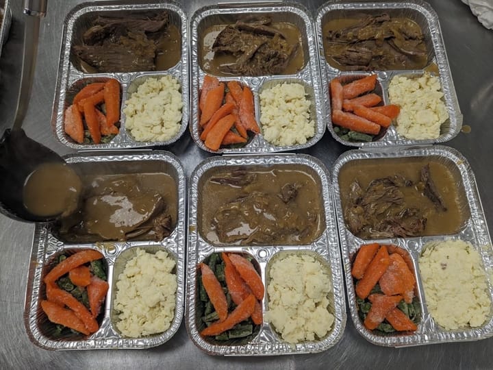 Prepared meal trays with roast beef, gravy, mashed potatoes, carrots, and green beans